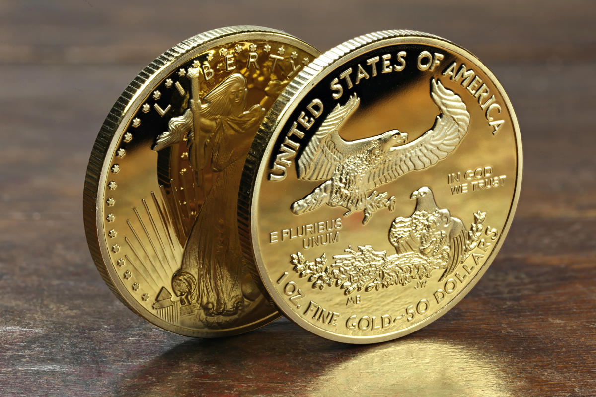 American Eagle Goldmünzen auf Holztisch Anlagemünze American Eagle in Gold – Vorder- und Rückseite mit den Motiven Lady Liberty und Adler an ihrem Horst.